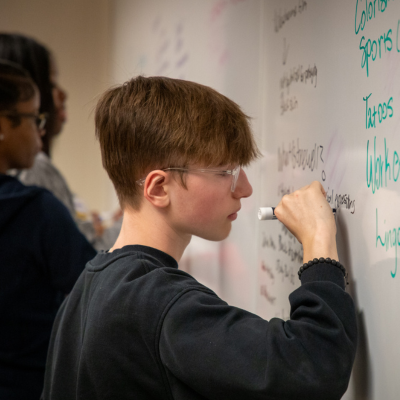 Student writing on a whiteboard with a marker.
